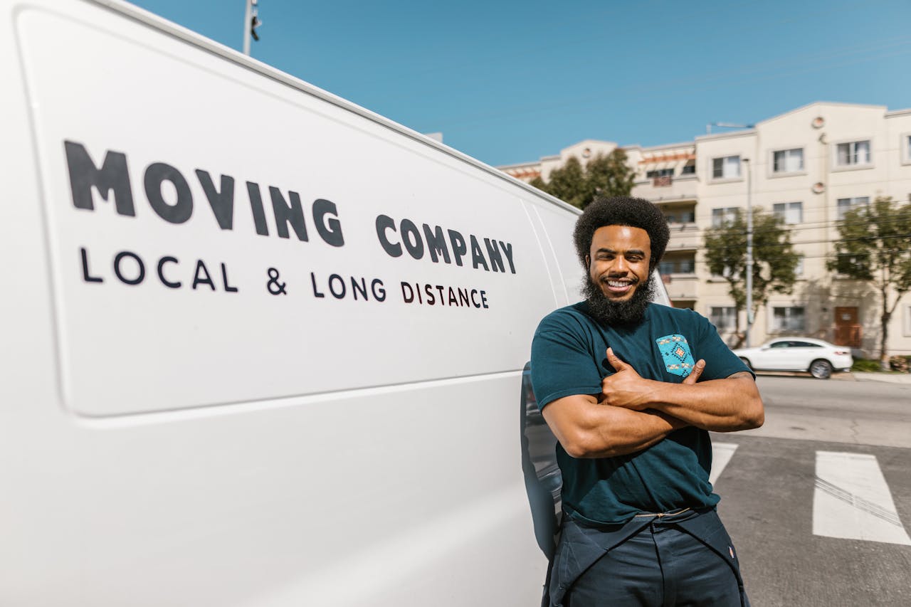 Man in Blue T-shirt and Black Pants Standing Beside White  Van